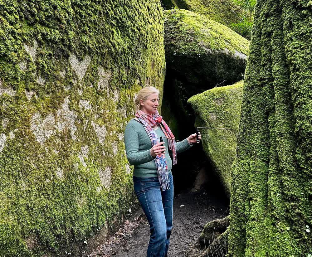 Eulalie Motte suit le mouvement de ses baguettes coudées entre deux rochers moussus